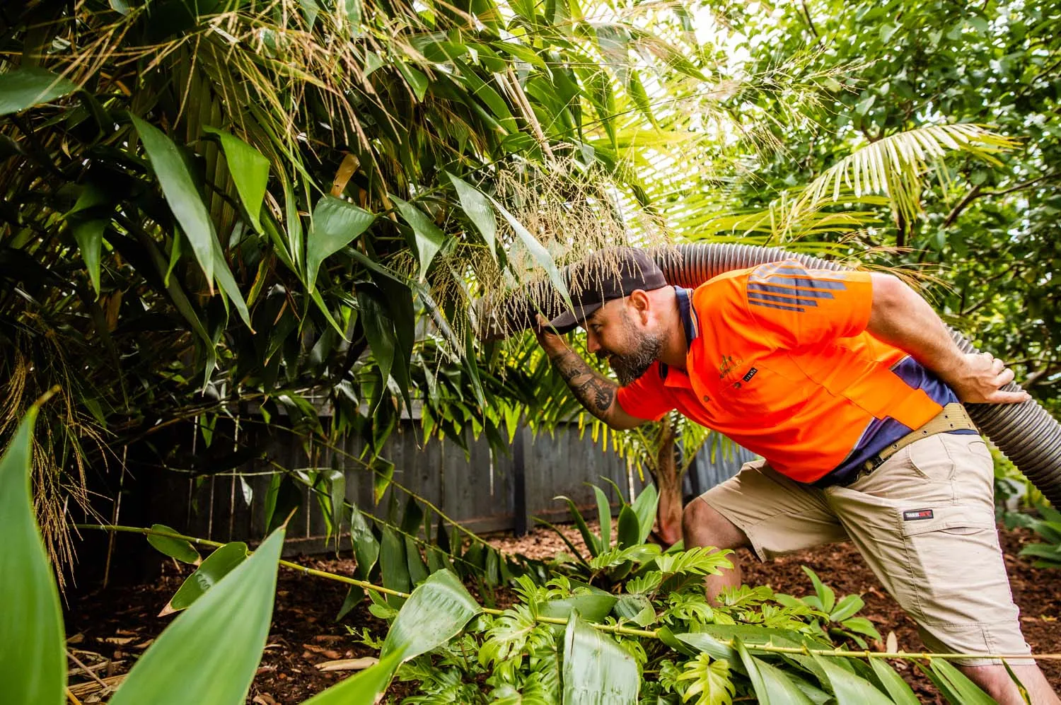AutoMulch operator blowing mulch through the hose into a leafy garden bed
